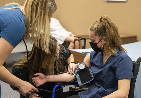 Nurse assisting students taking blood pressure