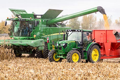 Combine and tractor harvesting in corn field